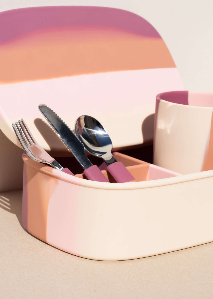 Grech & Co Blossom Ombre pink cutlery set stored in open matching silicone lunchbox with cup alongside on warm beige surface — sustainable kids mealtime set at Milimilu