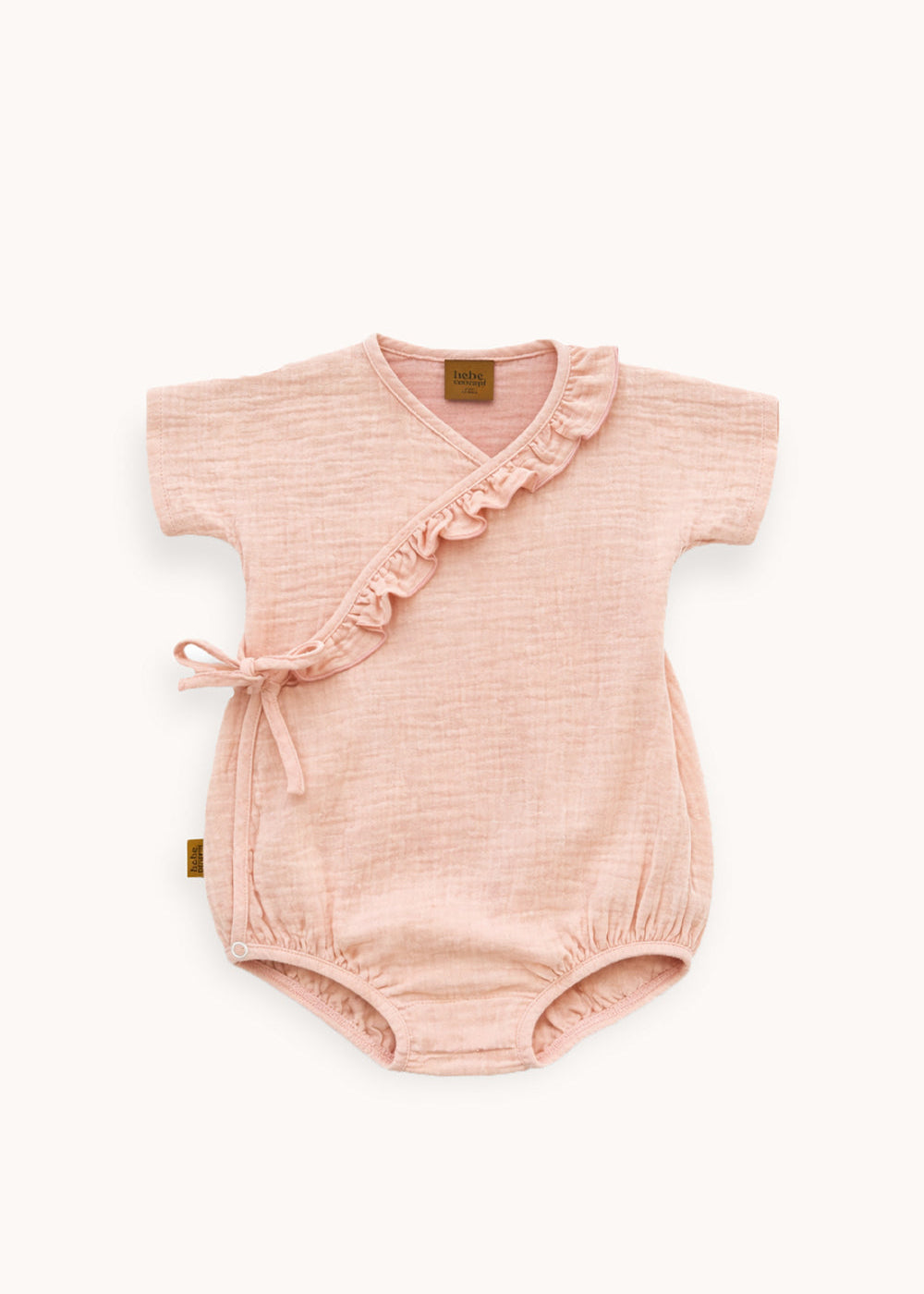 Close-up of ruffle detail on blush pink organic cotton baby romper