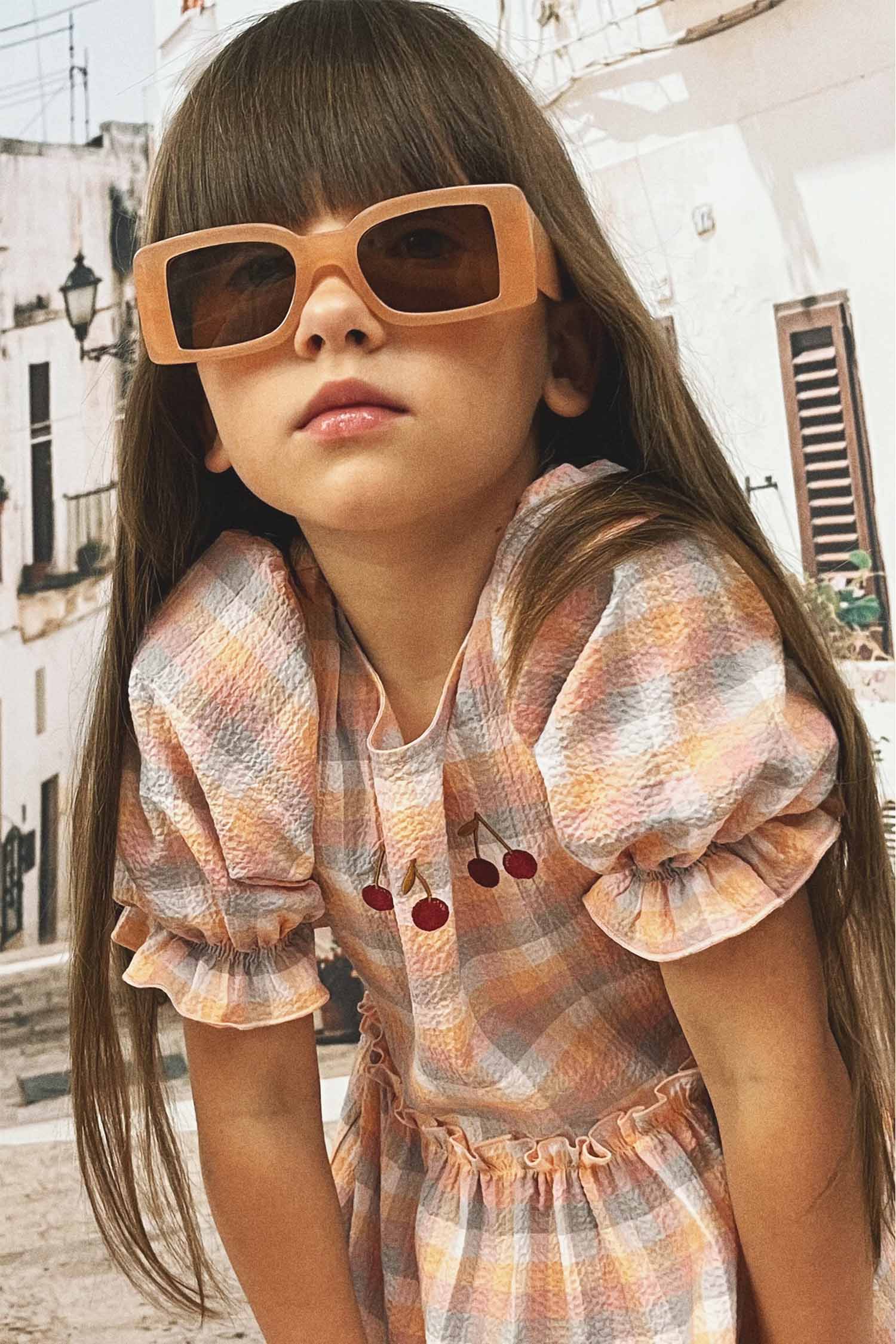 Girl in cherry print dress with puff sleeves, full length view showing comfortable fit and playful design.