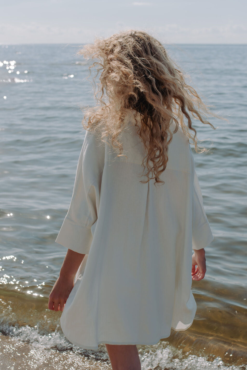 Elegant woman in off-white oversized linen shirt showcasing effortless luxury style - premium breathable fabric for all seasons.
