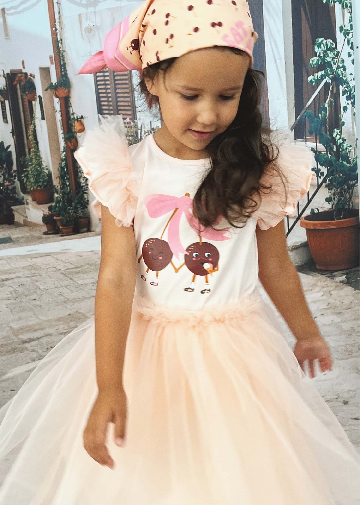 Girl wearing pink tutu skirt with cherry print, comfortable cotton lining for play