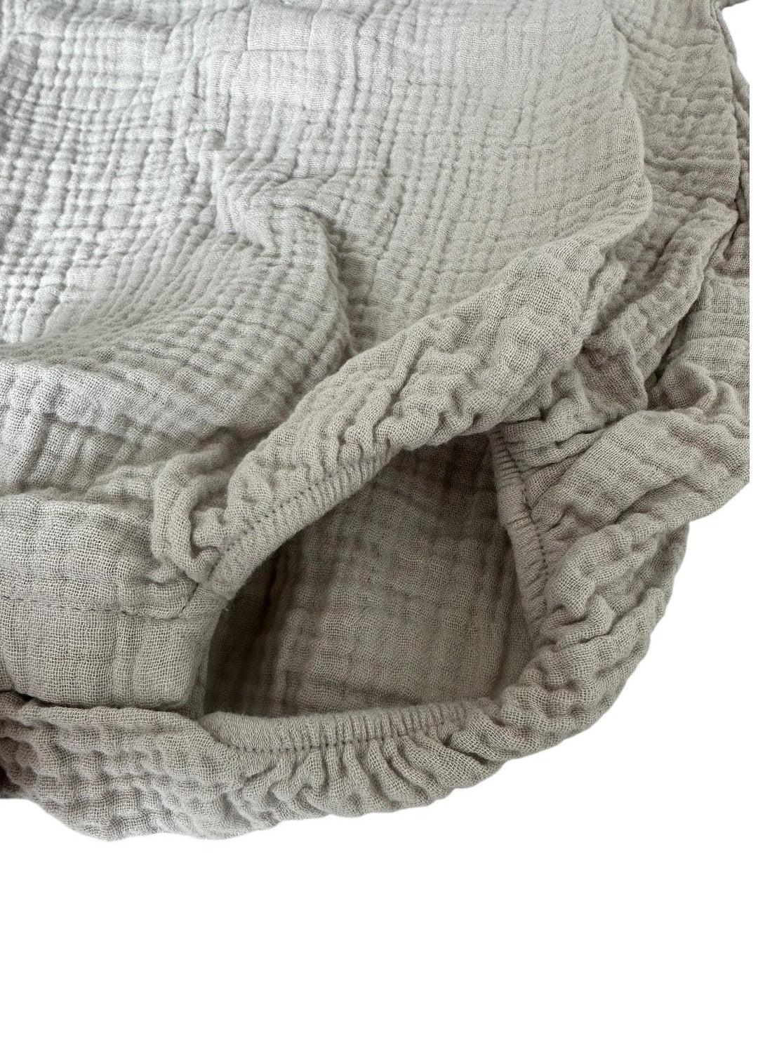 Light grey muslin baby romper detail, showcasing organic cotton texture and quality.