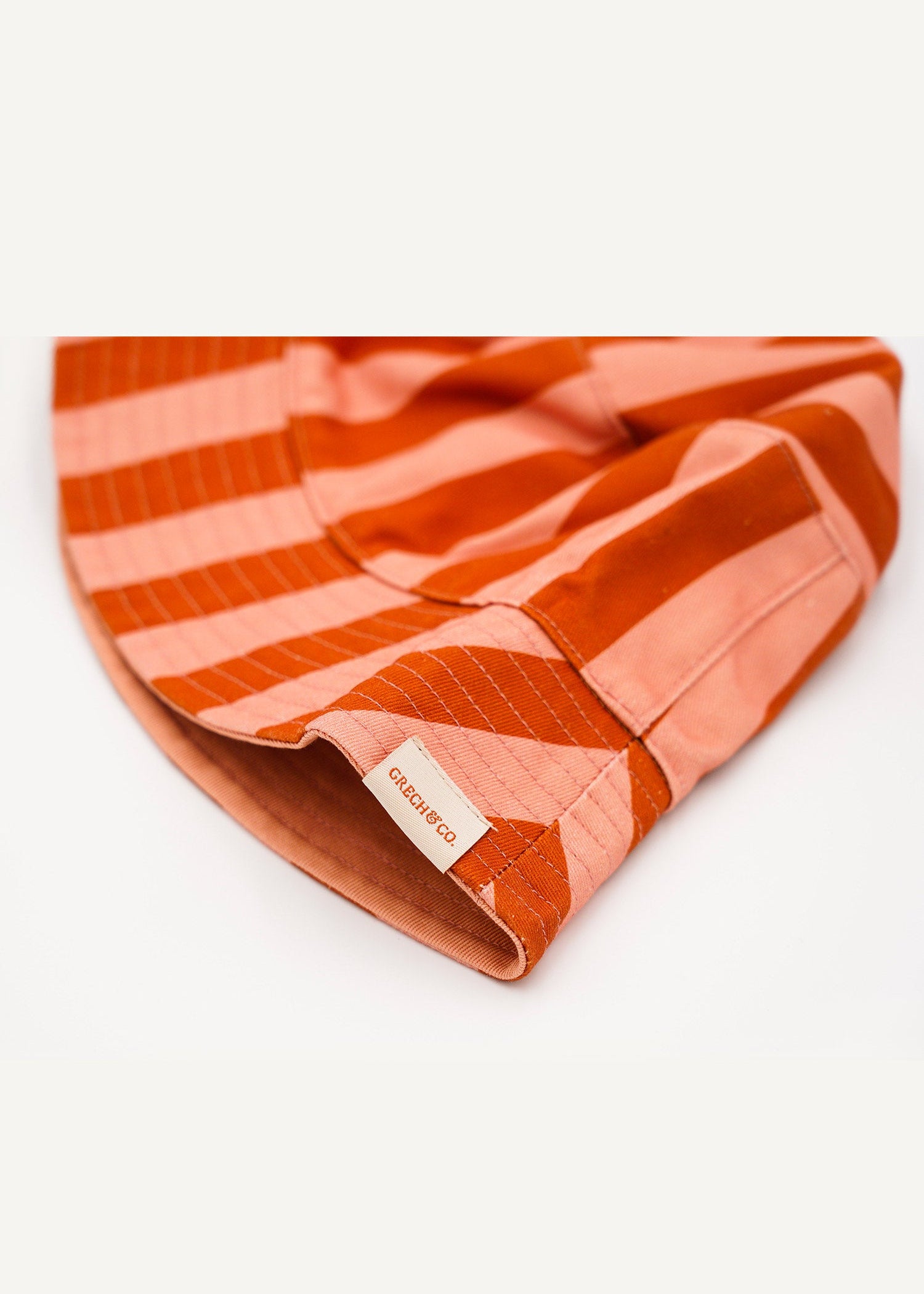 Organic cotton kids bucket hat - reversible design showing solid sunset color side