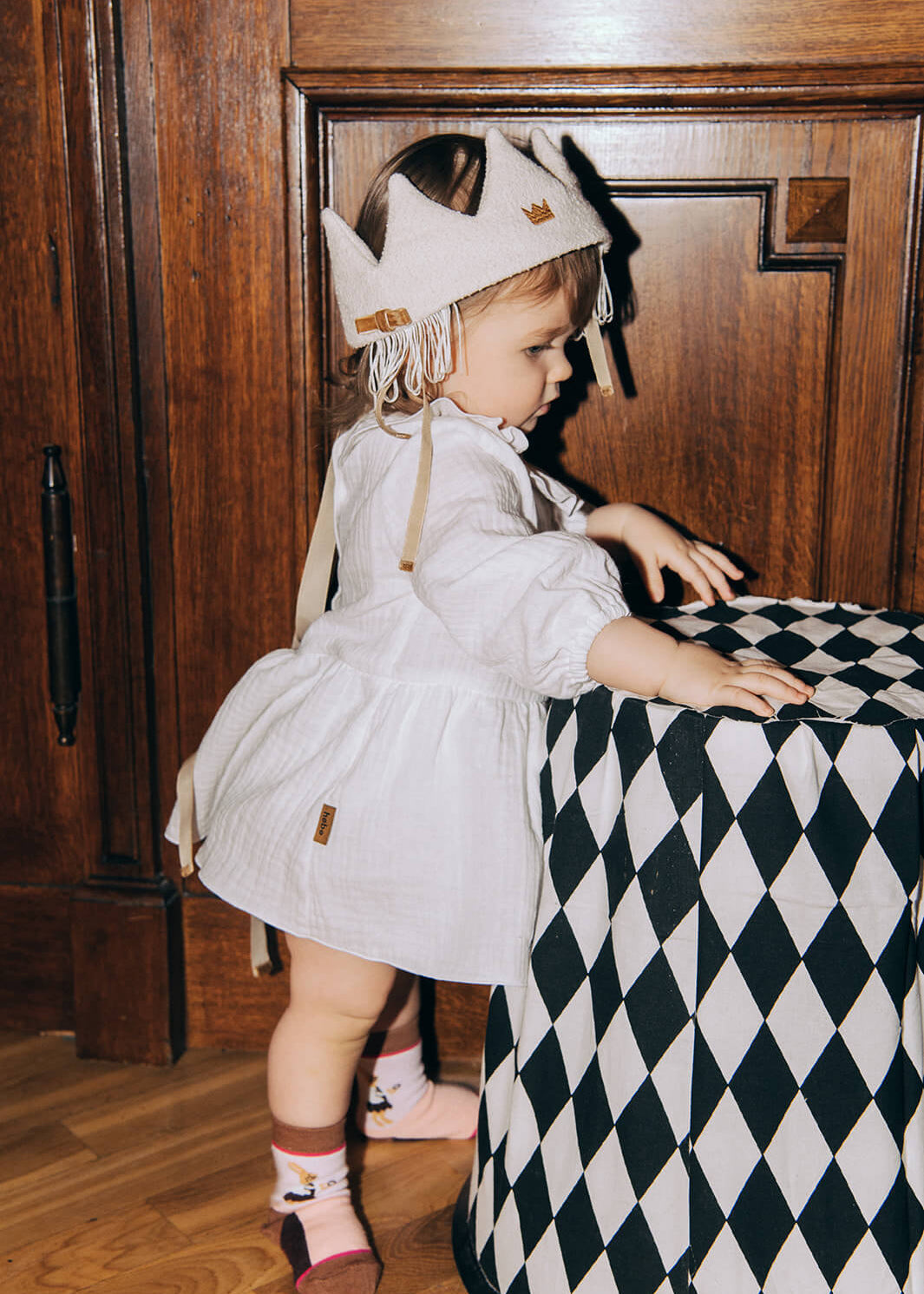 Close-up of white fabric princess crown with tassel details, HEBE hair accessory