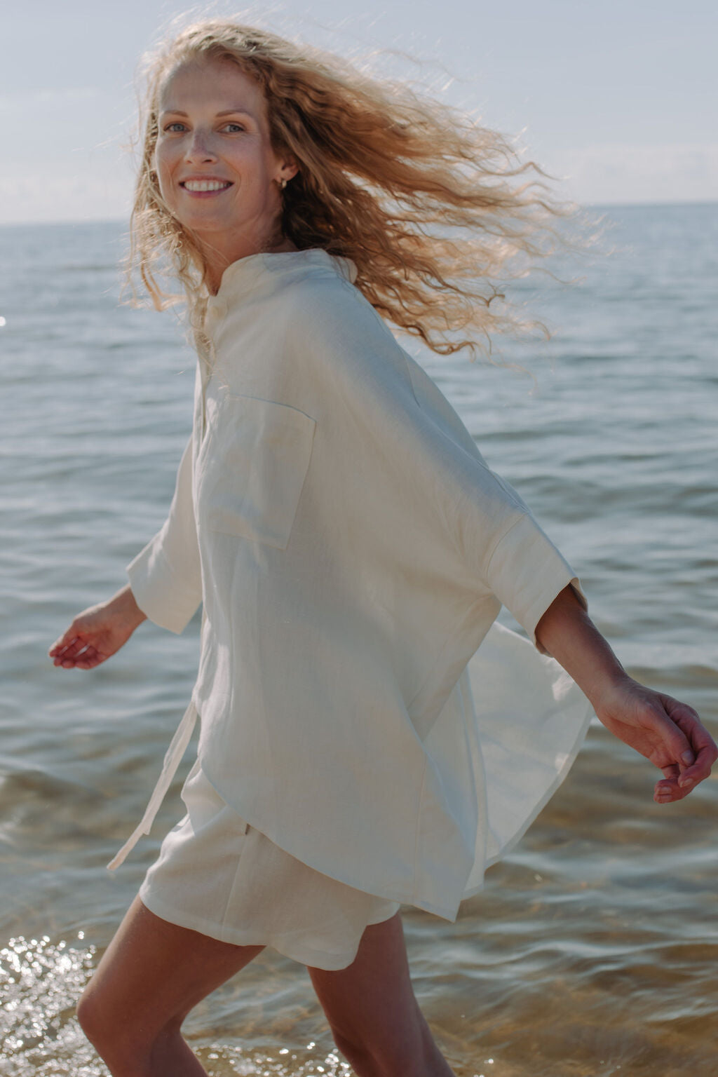 Off-white linen shirt worn as beach cover-up - versatile oversized top perfect for vacation and summer styling.