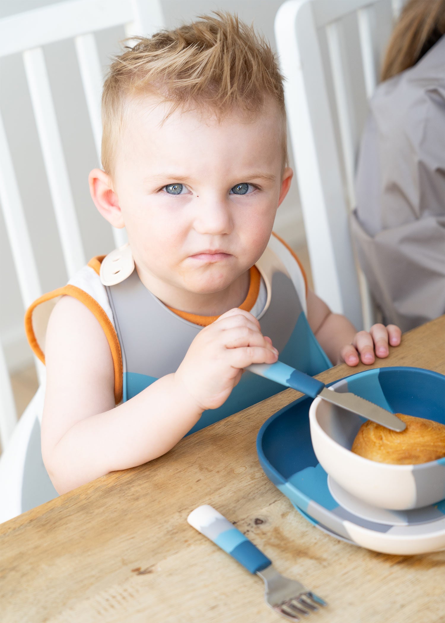 Toddler boy eating at table using Grech & Co blue Ocean Ombre suction plate and bowl with silicone bib and cutlery — baby led weaning tableware at Milimilu