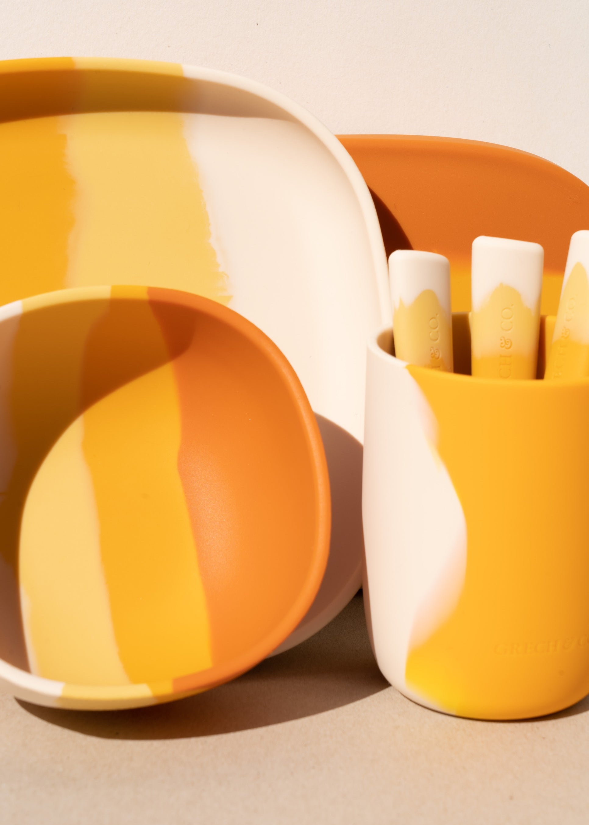 Grech & Co Sienna Ombre mealtime set with suction bowl, suction plate and cup holding cutlery in cream yellow amber and terracotta on warm beige background — sustainable kids tableware at Milimilu