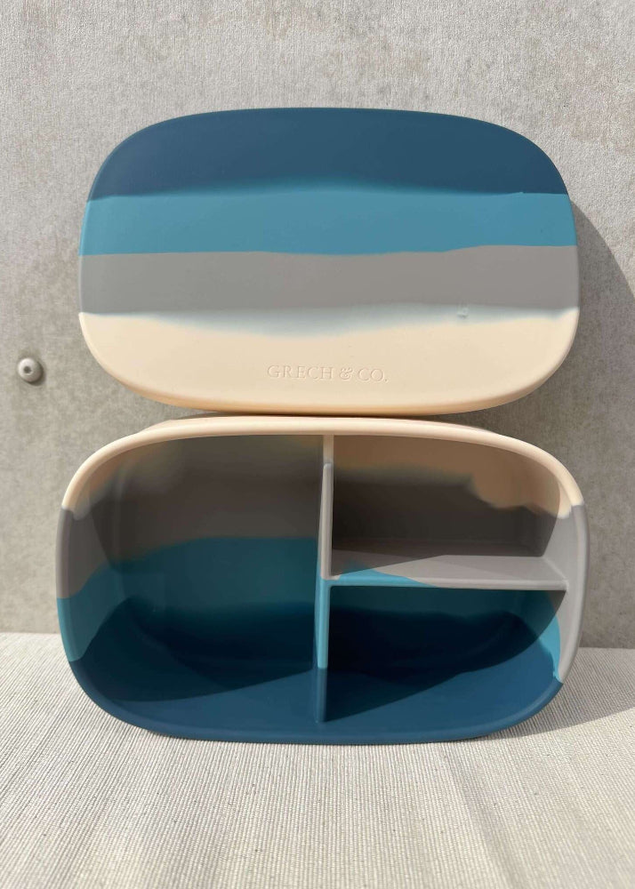 Grech & Co blue silicone lunch box open on linen surface showing 3 divided sections and Grech & Co embossed logo on lid — sustainable kids snack box at Milimilu