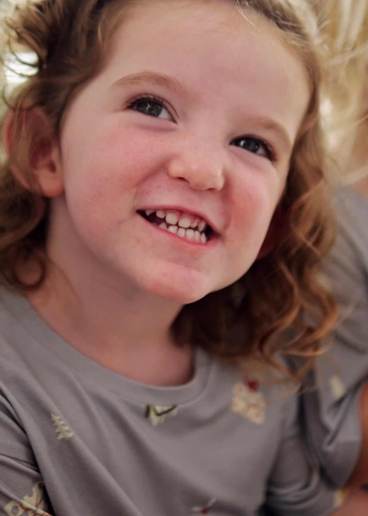 Girl smiling wearing sustainable bamboo Christmas t-shirt with Love of Gifting design, eco-friendly kids holiday clothing