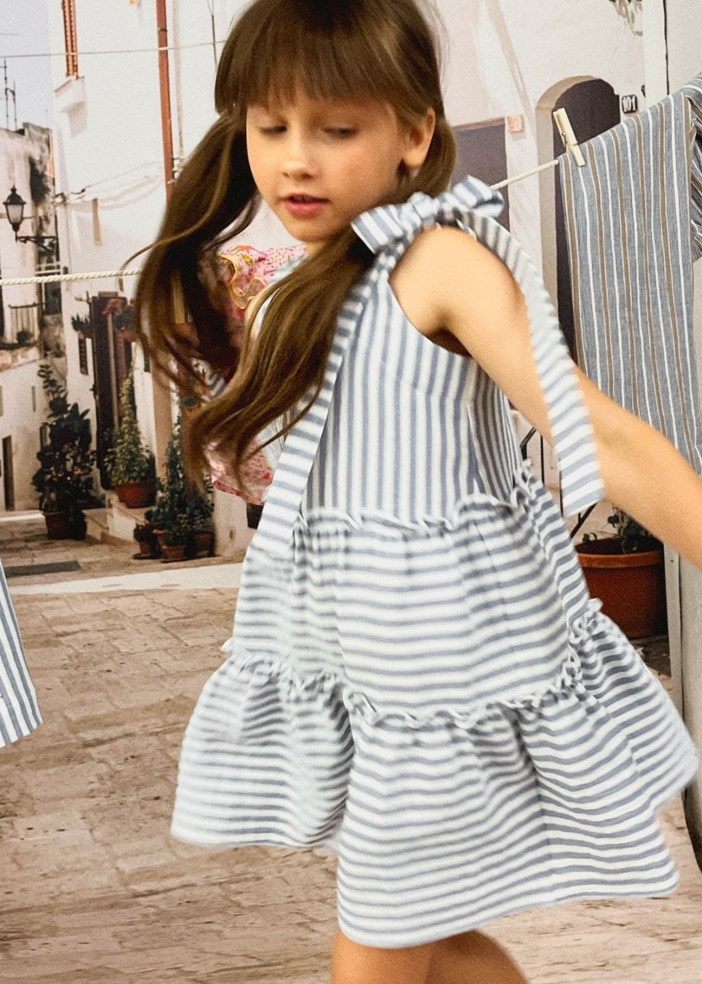 Girl wearing blue and white striped organic cotton twirl dress with adjustable straps