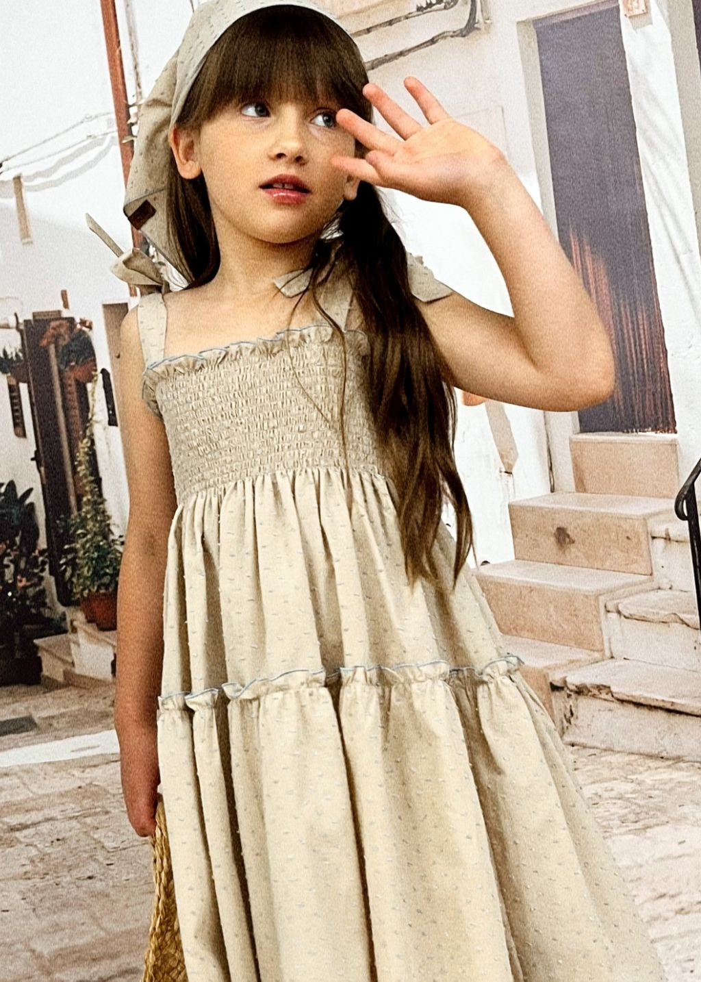 Girl wearing taupe dotted organic cotton summer dress with adjustable straps and stretchy top