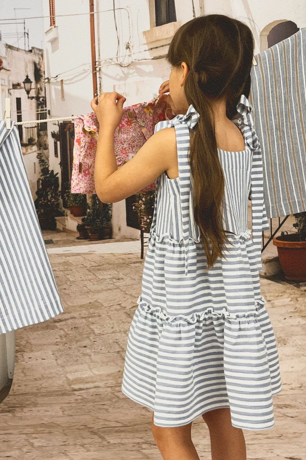 Girl twirling dress featuring blue and white stripes. Crafted from organic cotton, this exquisite summer dress is both breathable and lightweight online.