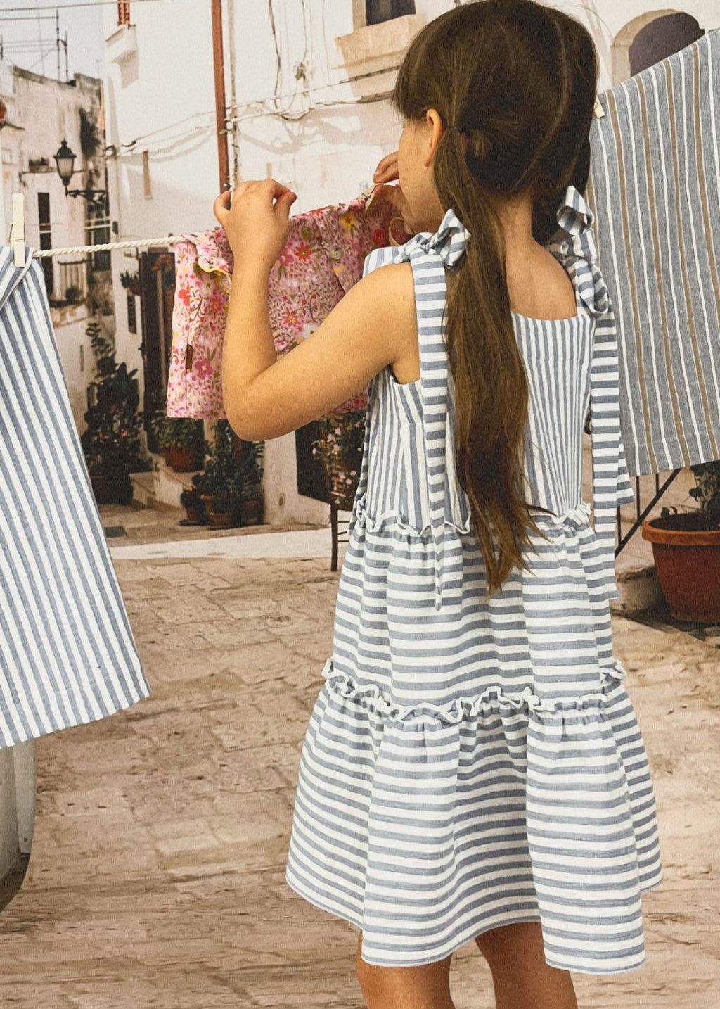 Back view of organic cotton girls' dress with blue and white stripes and adjustable straps