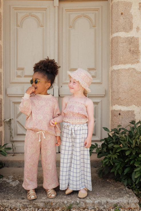 Our kid's bucket sun hat, which is not only lightweight and stylish but also comes in a beautiful print that your child will love. On one side, you have a charming pink daisy garden print, and on the other side, an off-white colour with a fringed edge. Designed by Louise Misha. Mini Me matching is available.