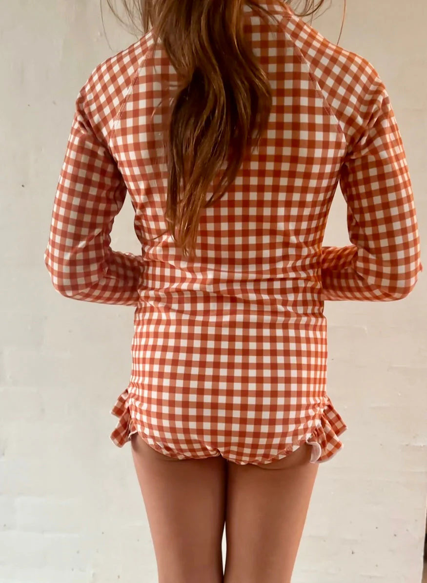 The long sleeve swimsuit for girls with rashguard and ruffle in Sienna Gingham by Grech and Co. Shop the best sustainable girl swimsuit online at MiliMilu.
