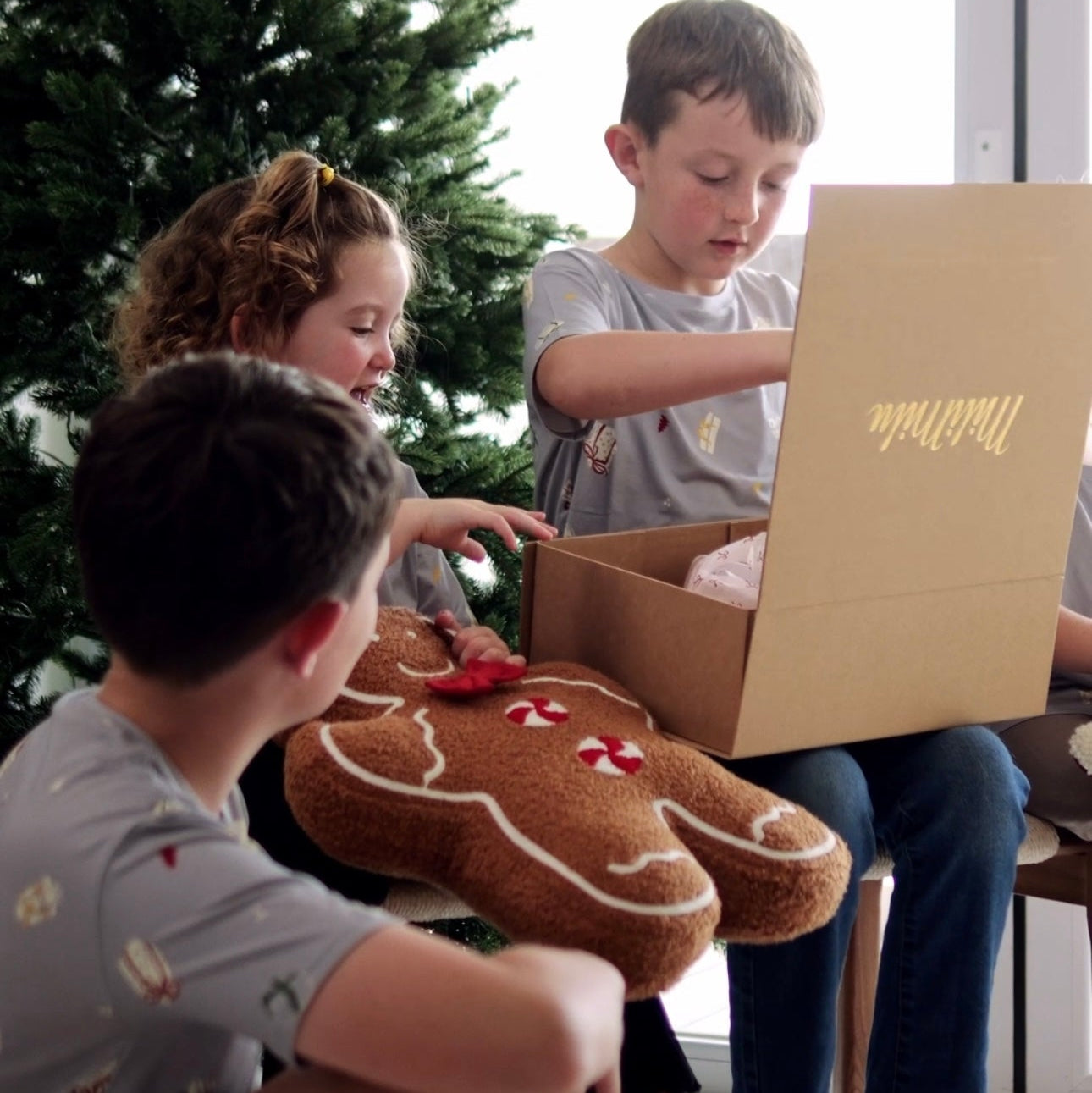 Kids wearing bamboo Christmas Tshirts are oprning Christmas presents