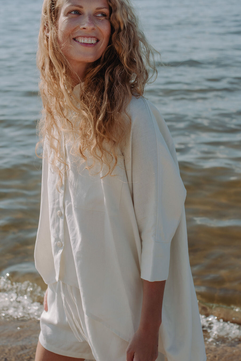 Woman wearing off-white oversized linen shirt - versatile summer top perfect for layering and all-day comfort.