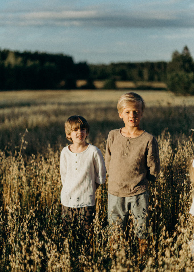 Kids wearing organic cotton muslin shirt in sand - unisex design perfect for summer and hot weather