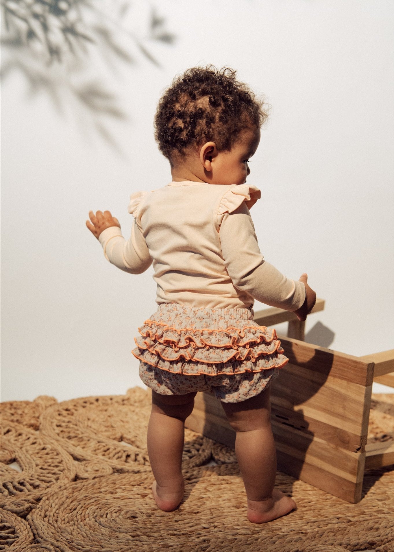 Pink baby bodysuit with ruffle shoulders by Hebe — GOTS certified, made in Latvia, sizes 2 months to 2 years