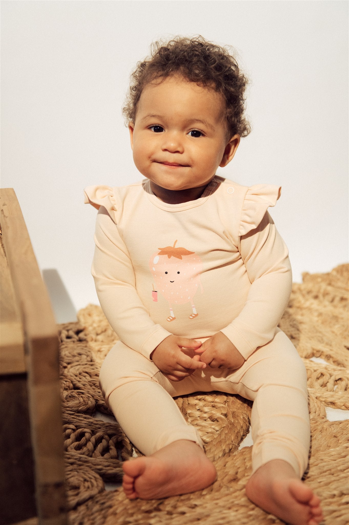Breathable organic cotton baby girls romper in light pink color with strawberry print and ruffles on the shoulders. The breathable baby clothing online.
