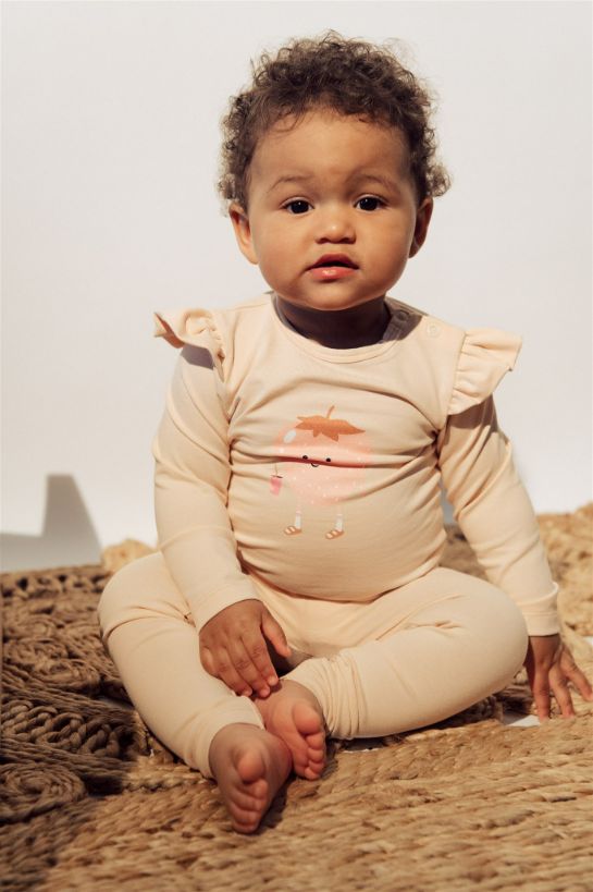 Breathable organic cotton baby girls romper in light pink color with strawberry print and ruffles on the shoulders. The breathable baby clothing online.