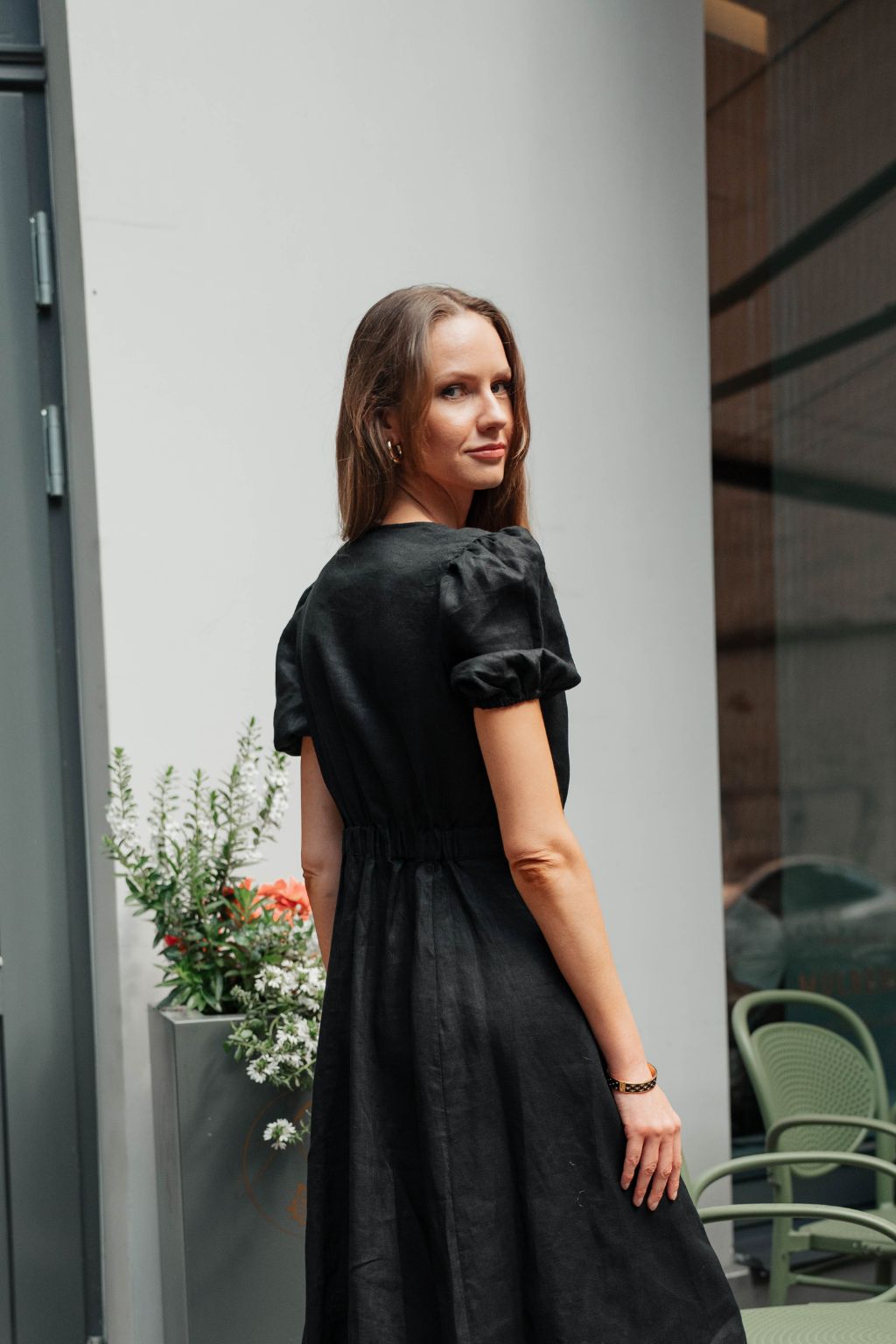 Black linen dress featuring distinctive puff sleeves and elegant silhouette.