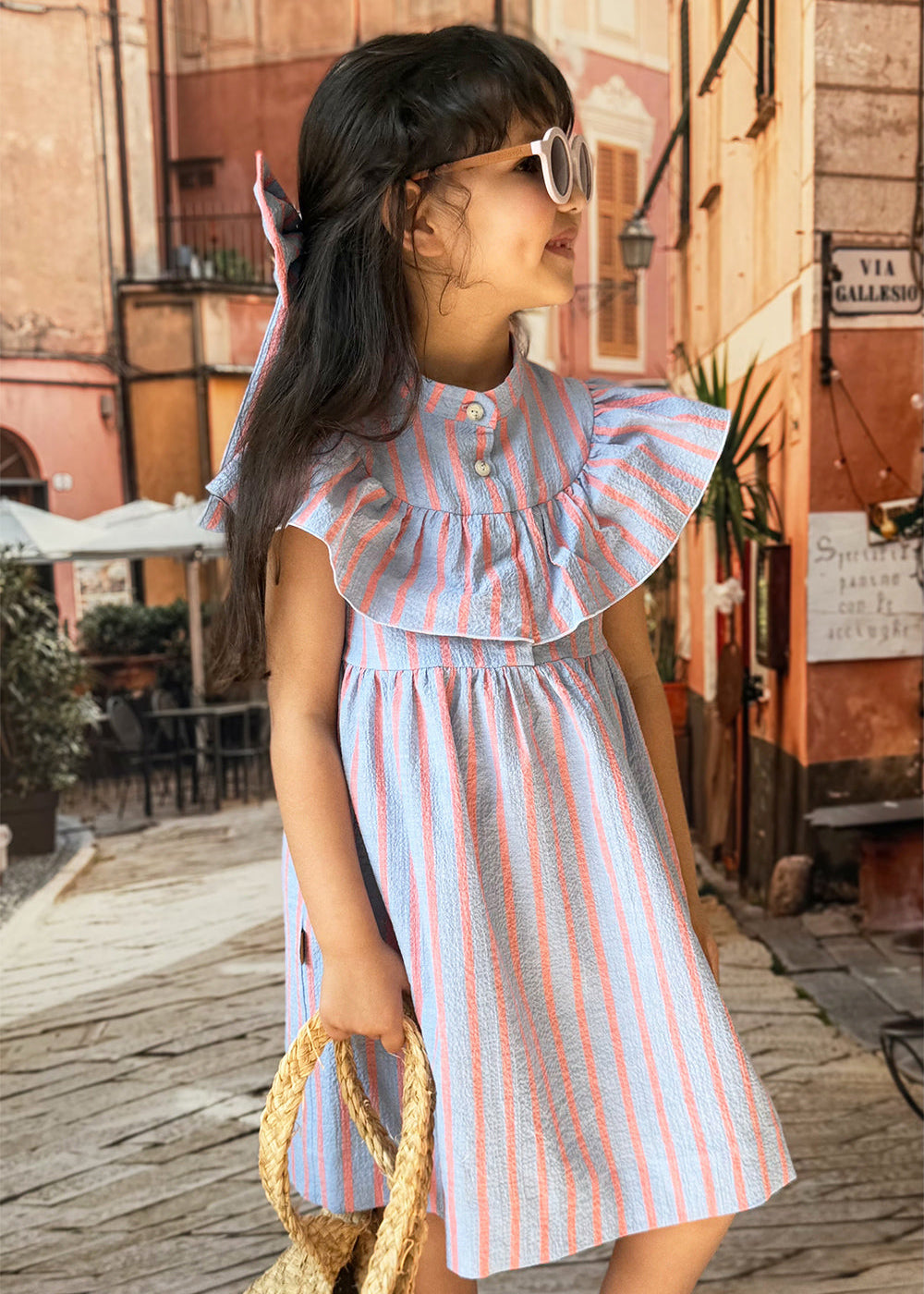 Girl wearing pink and blue stripe ruffle dress – organic cotton girls dress Mini Me collection by Milimilu