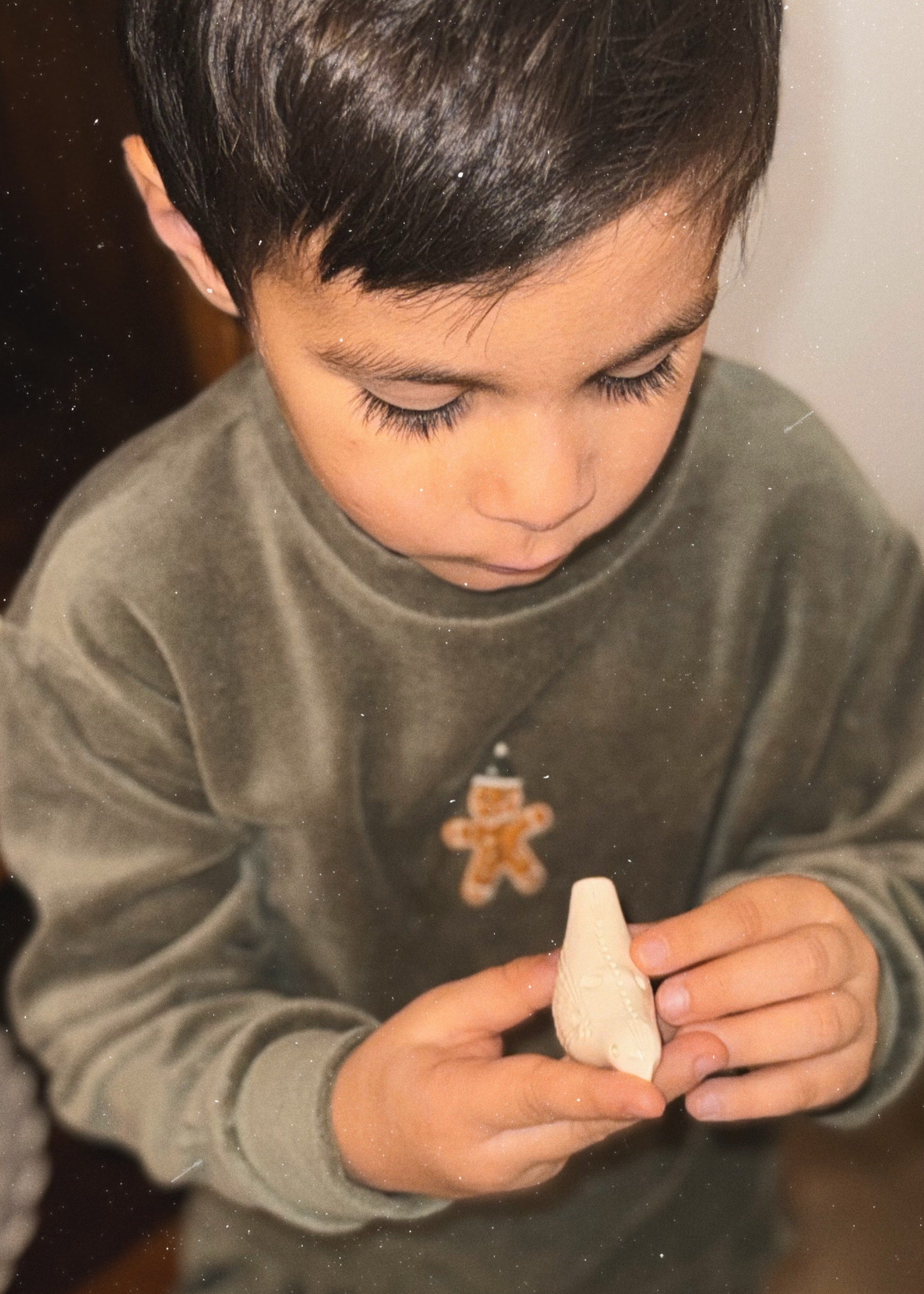 Close up of gingerbread man embroidery on kids green velvet Christmas sweater