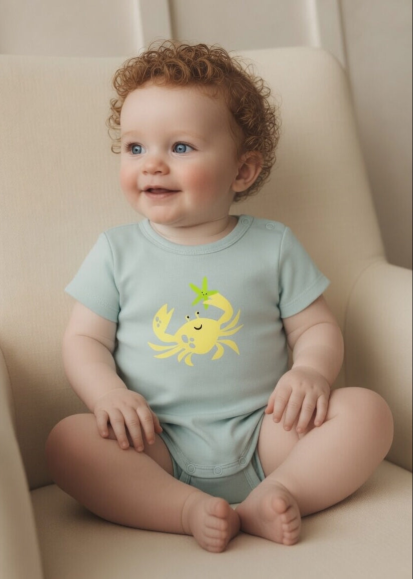 Close-up of yellow crab print on aqua blue baby bodysuit – soft breathable fabric for newborns and infants