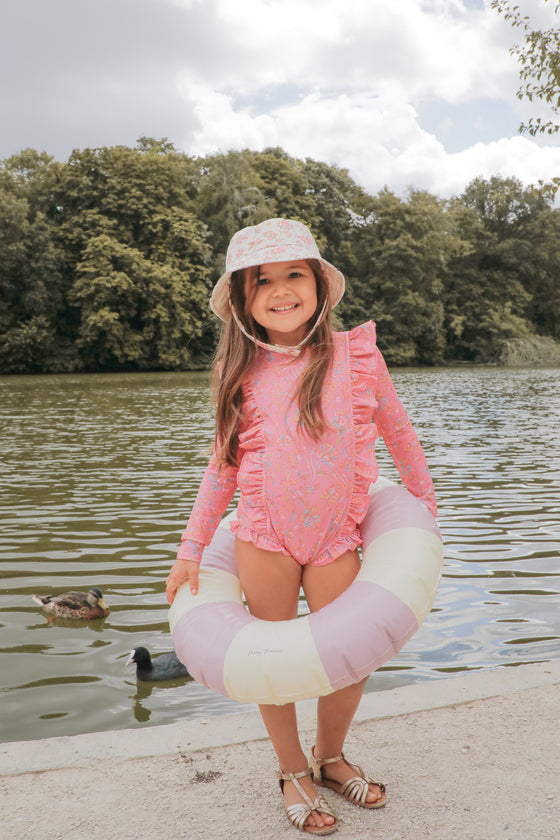 Sustainable girls swimsuit in pink flower pnrint. This girls long sleeve swimsuit is made from SPF 50 protective and recycled fabric designed by Louise Misha.