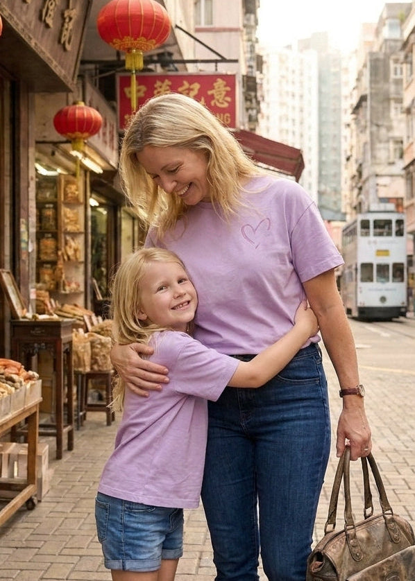 Woman and child hugging on a street with red lanterns and a tram in the background