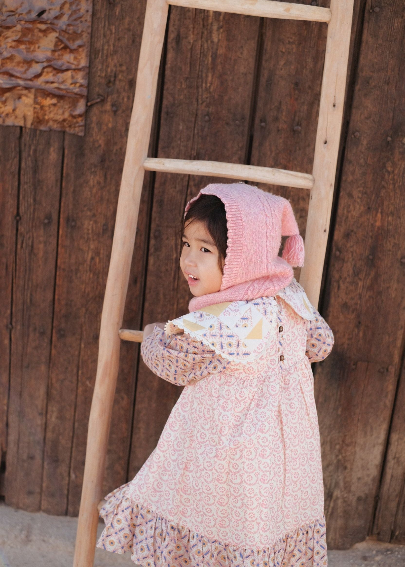 Girl wearing pink merino wool hood by Louise Misha - sustainable winter accessory