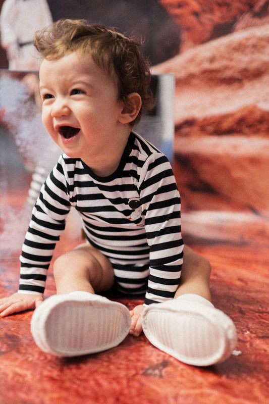 This bodysuite features black & white stripes with an astronaut print. Good for sensitive and eczema-prone skin in mind, this bodysuit is incredibly soft.