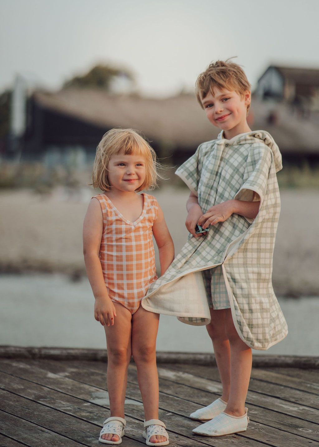 Child at beach wearing sustainable organic cotton poncho in green and white