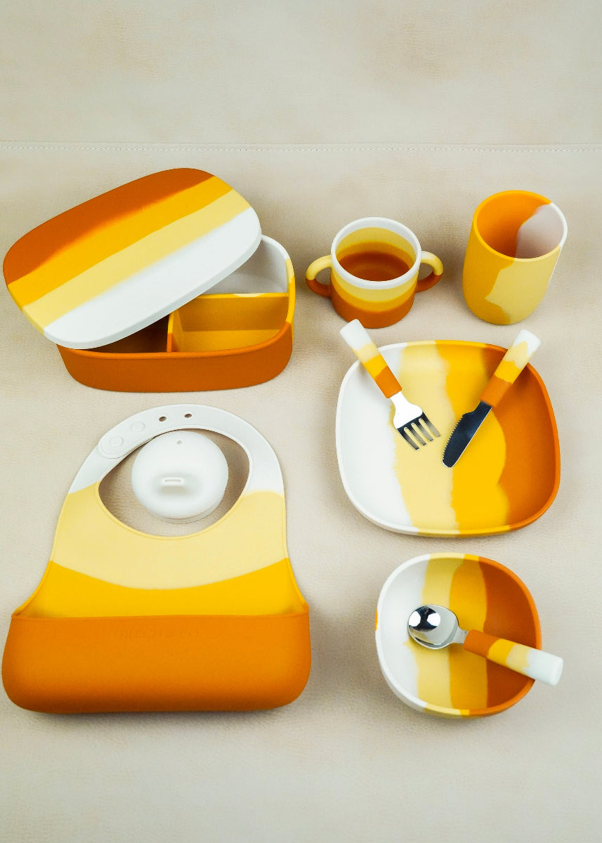 Full Grech & Co Sienna Ombre mealtime collection flat lay including suction plate, bowl, lunchbox, bib, cup and cutlery in orange yellow and cream — sustainable kids tableware at Milimilu