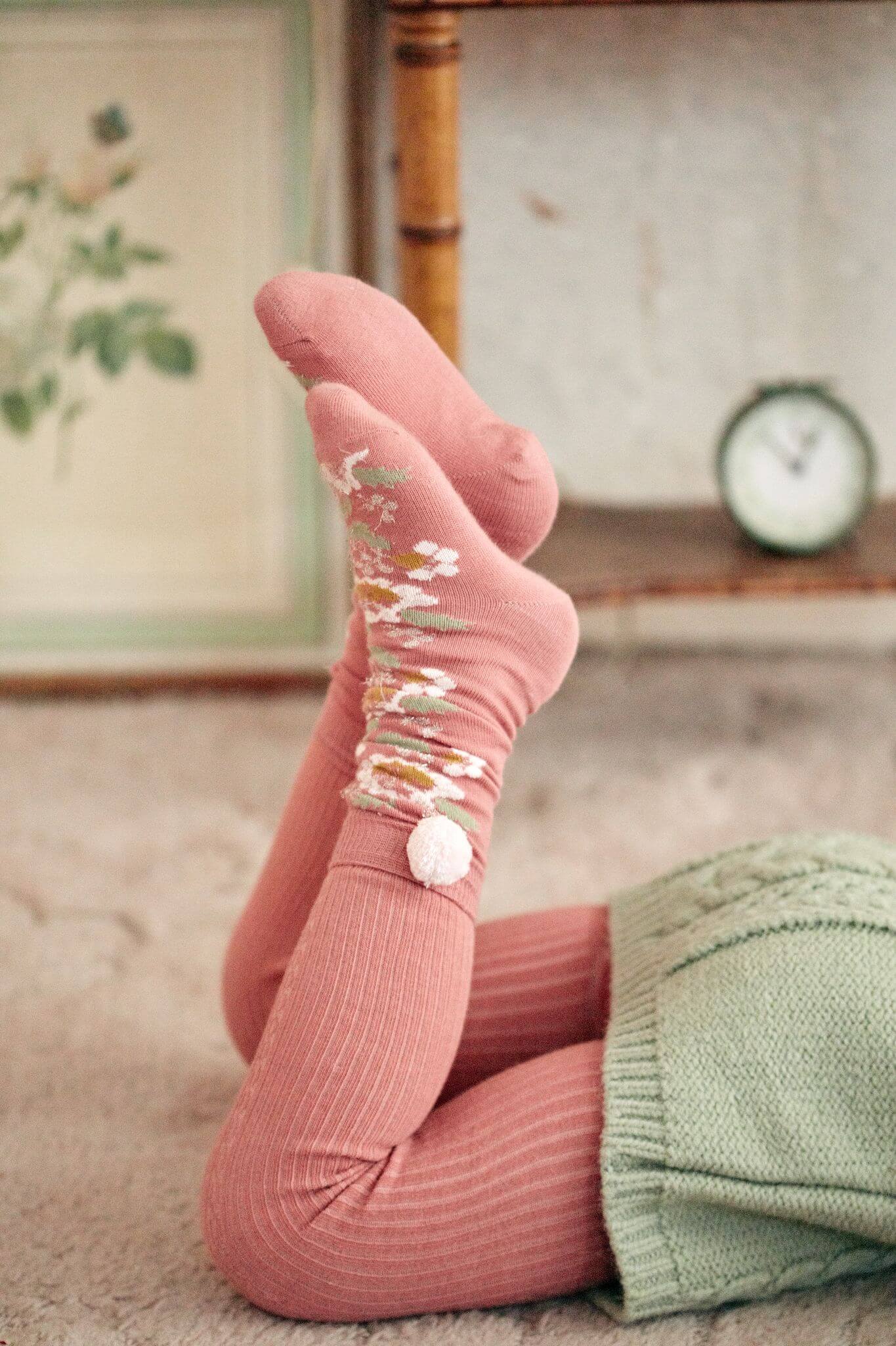 For every outfit, it's essential to have cute socks, and the Sienna socks in pink with floral patterns and handmade pompoms by Louise Misha.