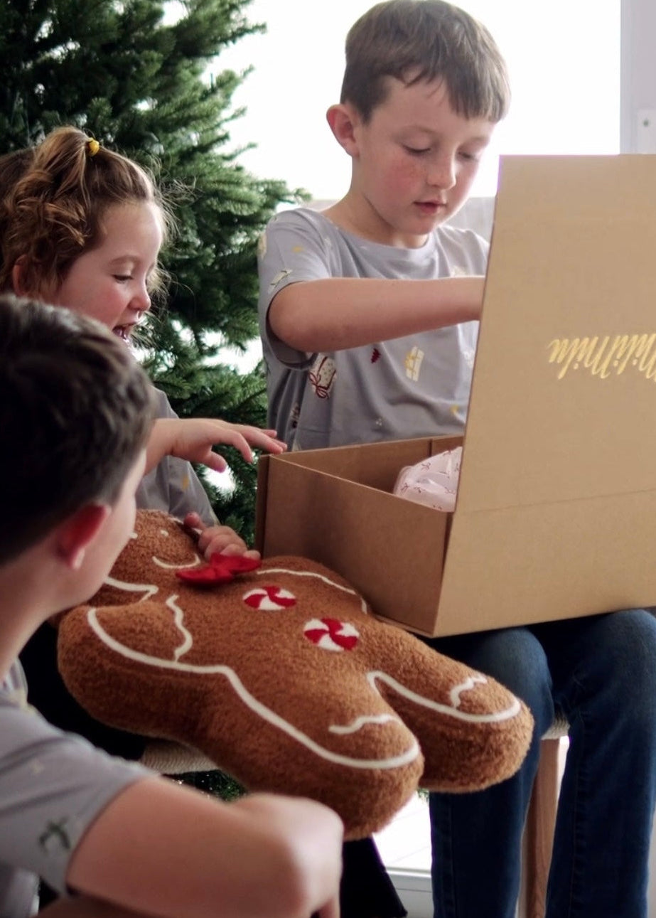 Kids wearing bamboo Christmas Tshirts are oprning Christmas presents