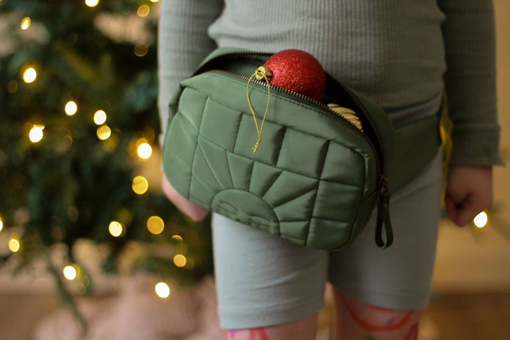 A sustainable crossbody/waist bag or fanny bag for women and kids in green colour from Grech&Co is durable and stylish.  Made from 100% Eco-Friendly Materials: Waterproof 100% recycled polyester outside and inside the fabric, organic cotton strap. Bronze buckles, rings, and zippers, and of course. Fanny bag for hiking.
