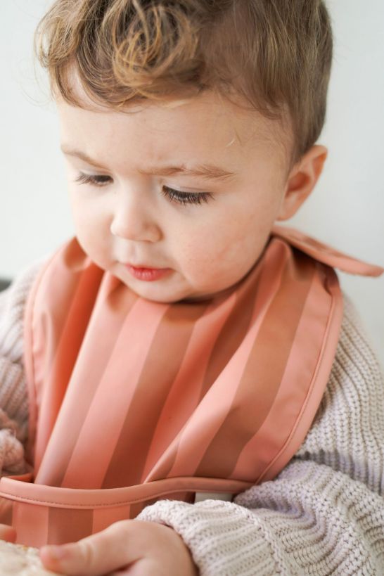 Grech & Co. easy-to-clean and store pink bib. Bib with pocket and water-resistant recycled oeko tex material. Practical and stylish sustainable baby pink bib.